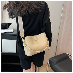 Close-up of beige lychee grain leather bucket bag with wide strap and gold hardware