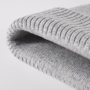 Close-up of light gray knitted winter beanie with premium ribbed texture and soft wool blend