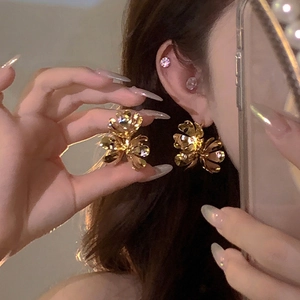 Close-up of golden metallic flower earrings worn by a model in warm vintage lighting