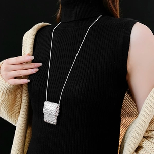 Silver woven square pendant snake chain necklace styled on a beige knitted cardigan