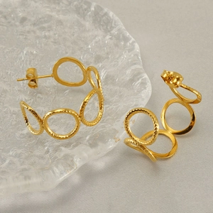 Golden round hollow double-loop earrings on a textured glass tray with clear metal detail