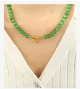 Close-up of green cat eye stone beaded necklace with golden spring clasp on a model