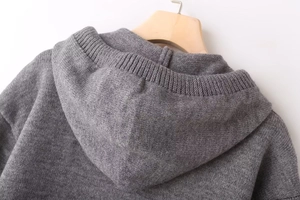 Detailed macro shot of the grey knitted texture and hooded neckline of this casual sweater