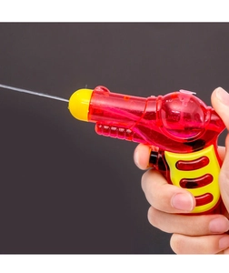 Action shot of small red water gun toy shooting a clear stream on gray background