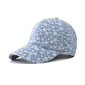 Detail view of light blue denim baseball cap featuring white floral bleach pattern