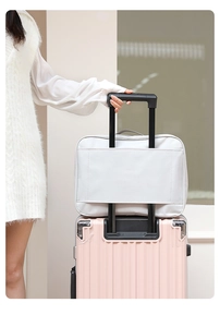 Cute cartoon travel bag attached to a pink suitcase handle in a cozy indoor setting