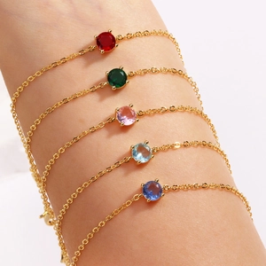 Close-up of colorful gemstone bracelets on wrist with gold chains in five vibrant colors