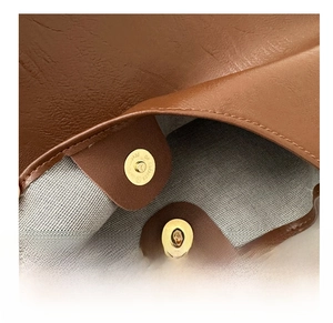 Close-up of golden magnetic snap closure on high-quality brown textured leather tote bag
