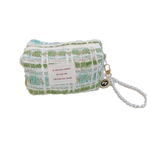 Elegant green tweed mini bag with pearl handle and bow charm on white background