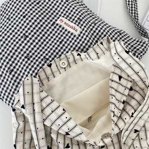 Detail view of canvas tote bag featuring magnetic closure, inner zipper pocket and woven label