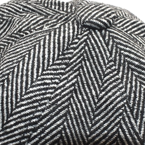 Gros plan du motif à chevrons et du bouton en tissu sur la casquette plate d'hiver
