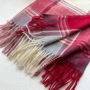 Macro shot of thick plaid scarf featuring red and grey patterns with fringe detail