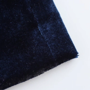 Detailed macro view showing the soft texture of dark blue velvet fabric on a midi dress