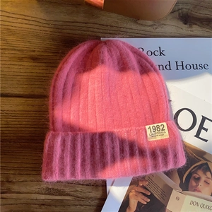 Detailed macro shot of pink mohair beanie with 1982 California label on wooden desk