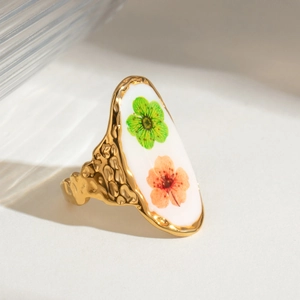 Macro view of gold hammered ring featuring a white oval inlay with real dried flowers