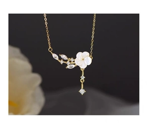Macro detail of S925 silver plum blossom necklace with tassels and mother of pearl flower