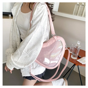 Detail of pink heart-shaped ita bag with transparent mesh front worn by a model