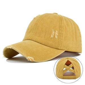 Close-up of distressed yellow washed cotton ponytail baseball cap with criss-cross back detail