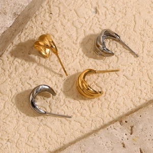 Gros plan de boucles d'oreilles citrouilles dorées et argentées sur fond de pierre