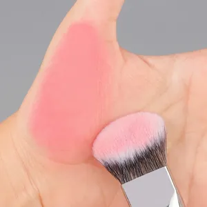 Pinceau fond de teint biseauté aux poils rose dégradé appliquant du fard sur la peau