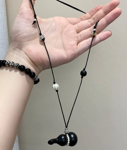 Close-up of vintage black gourd pendant on adjustable wax rope with decorative beads