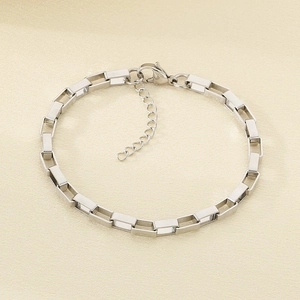 Detailed macro shot of silver rectangular link chain bracelet with lobster clasp and drop charm