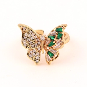 Macro detail of butterfly ring with green and white zircons in gold setting