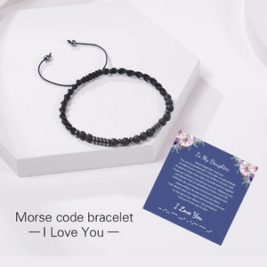 Détail du bracelet code Morse avec pierres de lave sur un support en pierre blanche