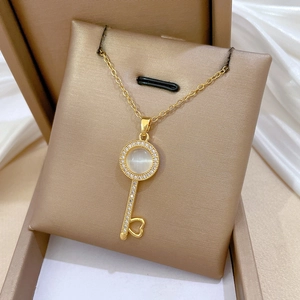 Golden opal key necklace with sparkling crystals and heart detail on white silk padding