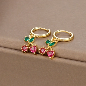 Close-up of cherry-shaped huggie earrings with red and green gemstones on a jewelry box