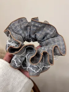 Detail of vintage blue-grey plaid hair scrunchie with white lace trim and brown piping