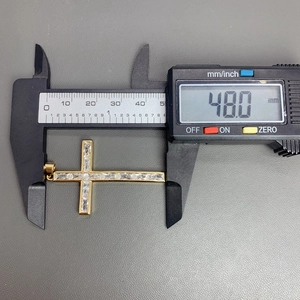 Close-up of 48mm gold cross pendant with baguette-cut zircons measured by digital caliper