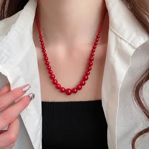 Ensemble de colliers de perles rouges dégradées pour femmes portés sur une chemise blanche
