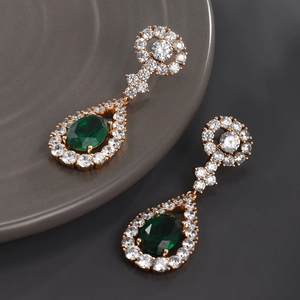 Macro shot of long emerald green teardrop earrings with gold plating and white zircon stones
