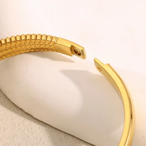 Macro shot of 18K gold-plated bangle featuring inner honeycomb texture and mechanical clasp