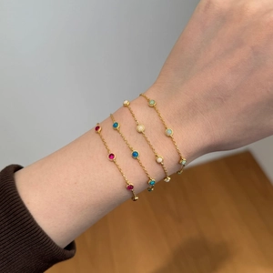 Detailed close-up of four gold silver bracelets with colorful opal stones on a wrist