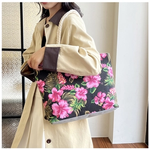 Detail view of large tote bag with pink hibiscus print and rope handles on a model