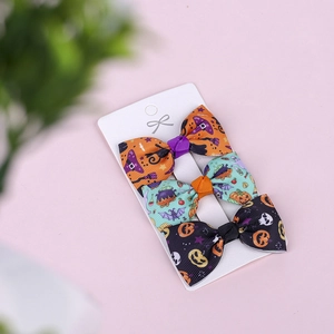 Detailed view of Halloween bow hair clips with pumpkin and bat prints on card