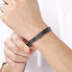 Close-up of minimalist 3mm black titanium steel round bangles worn by a model