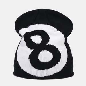 Close-up of black knitted beanie featuring white 8-ball pattern and ribbed texture