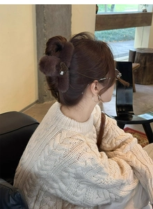 Deep brown plush claw clip with leopard heart detail worn on a model's hair in winter