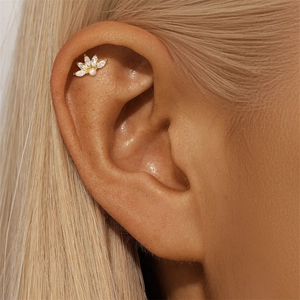 Close-up of lotus shaped silver stud earring with white zircons and pearl on ear