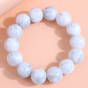 Detail view of large white marble textured round beads on a minimalist elastic bracelet