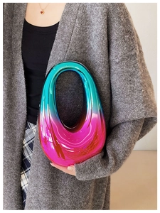 Close-up of blue and pink gradient acrylic handbag held by model in indoor setting