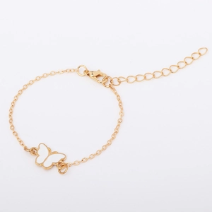 Detail of adjustable gold chain bracelet featuring white enamel butterfly and lobster clasp