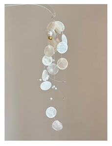Macro detail of round translucent shell pieces and pearls on a bohemian wind chime