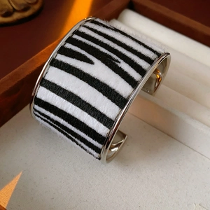 Macro view of wide cuff bracelet featuring zebra-print flocking and silver metal edges