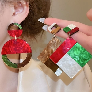 Macro shot of colorful resin acrylic geometric earrings with marble texture on ear lobe