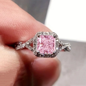 Détail d'une bague avec gemme rose taille coussin et anneau torsadé serti de diamants