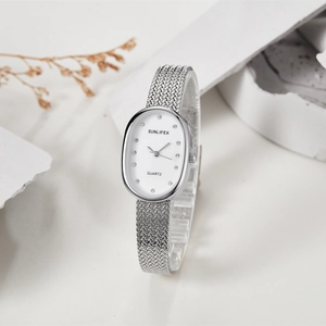 Macro view of oval silver quartz watch with rhinestone markers and woven metal strap
